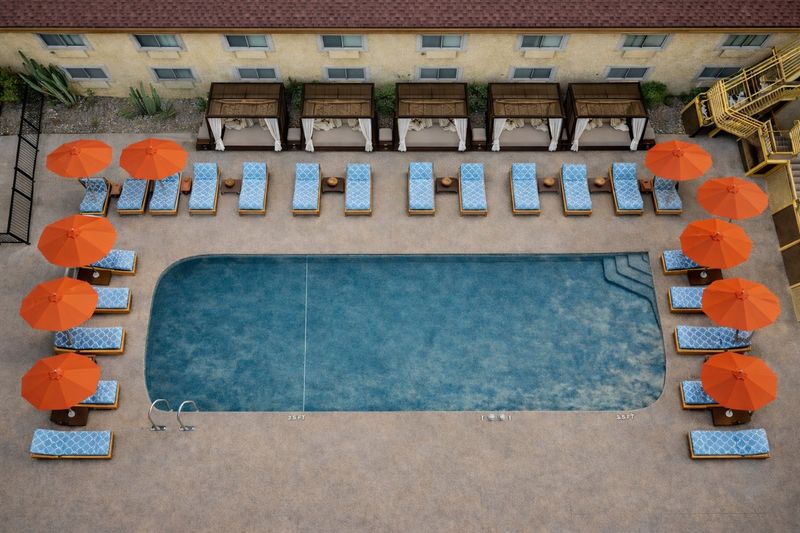 Pool deck with orange umbrellas, loungers and cabanas